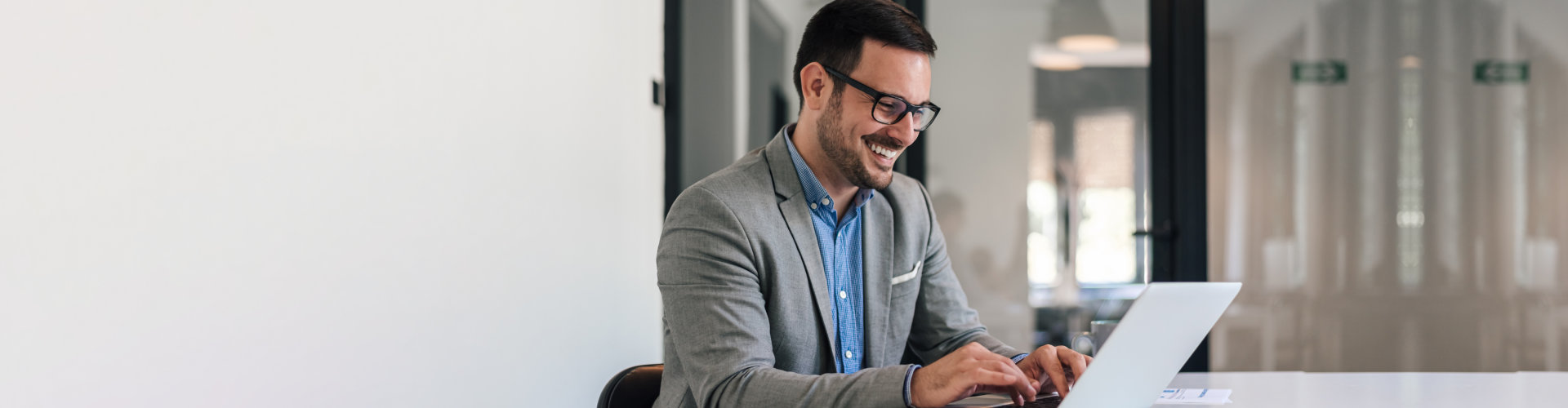 Cheerful male businessman entrepreneur professional working on laptop while sitting at office desk